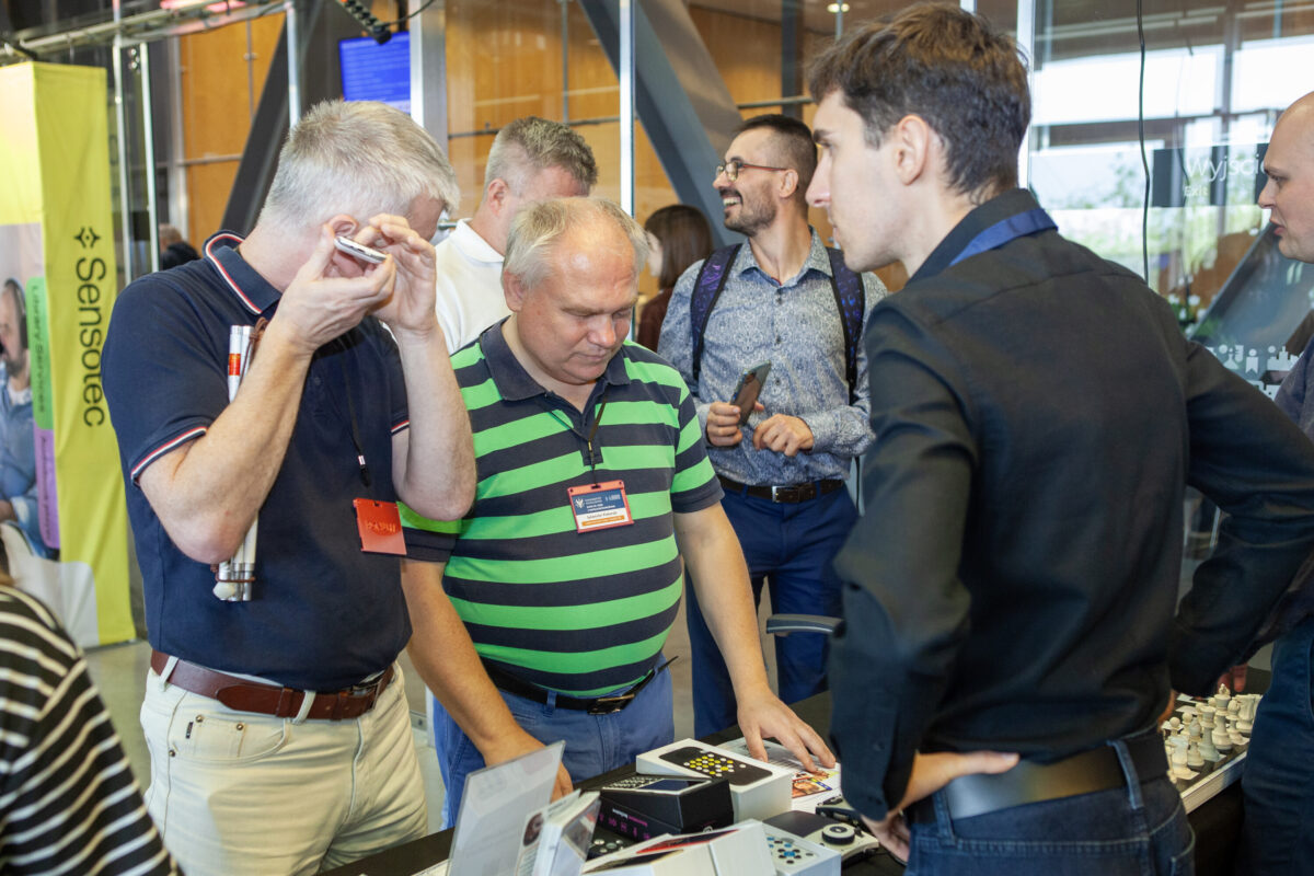 Grupa zwiedzających ogląda i testuje urządzenia na stoisku Sensotec podczas Accessibility Expo 2025.