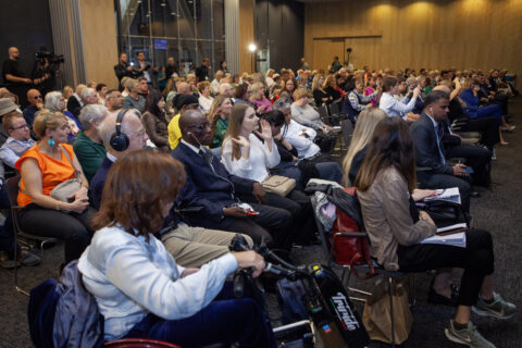 Uczestnicy konferencji REHA 2025 na widowni; na pierwszym planie kobieta na wózku, obok uczestnik w słuchawkach.